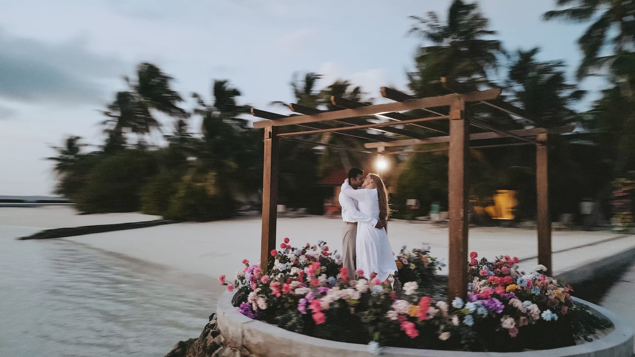 Aerial view of couple under floral pergola by lagoon